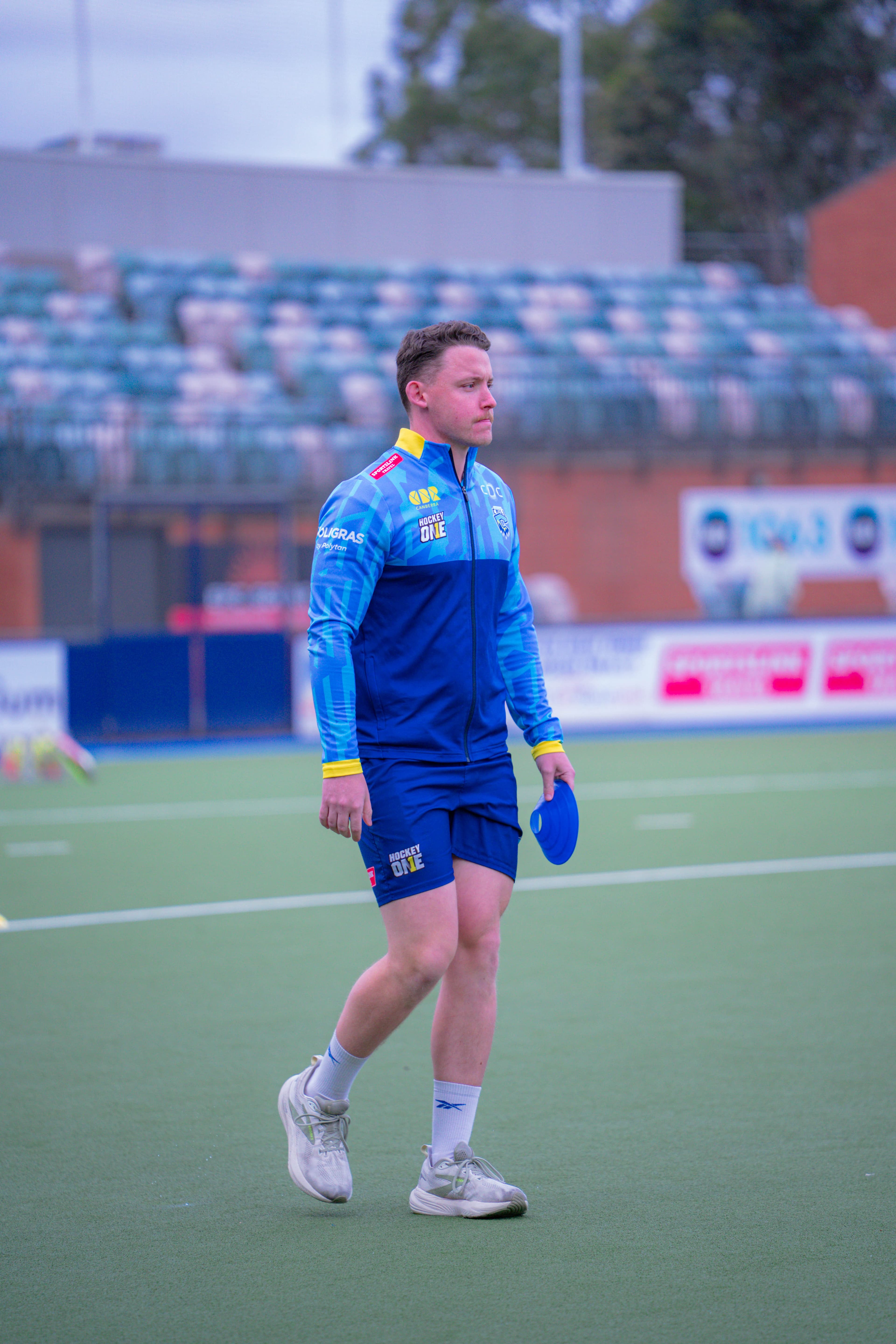 Coach observing field sport preparation on the pitch.